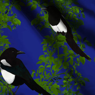 pattern of 2 magpies on green branches with indigo background shown on fabric