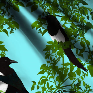 pattern of 2 magpies on green background with pale blue background shown on fabric