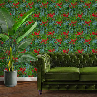 pattern of red berries and green leaves on a blue background shown as wallpaper with green sofa and plant